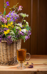 Bouquet of medicinal herbs in basket and herbal tea