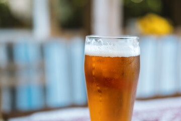 A mug of cold craft beer on a table outside. Blurred background