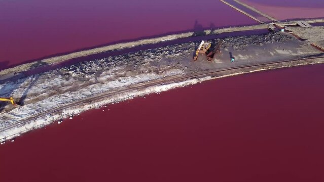 View of a salt tower between two pink salt lakes with an escavator ext to it.
