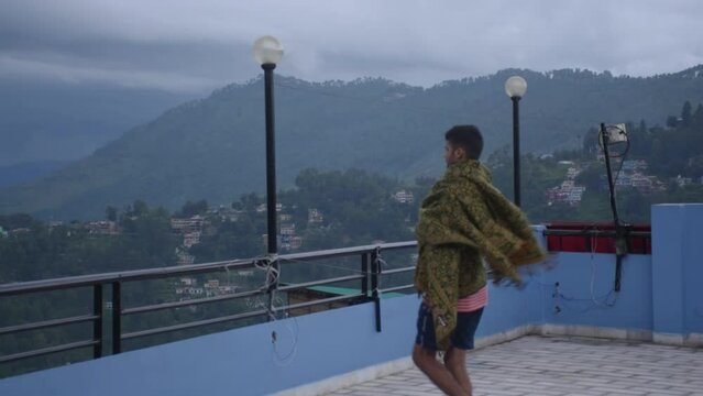 A young man who stands enjoying the air and the beauty of the hills in the morning, Almora, Uttarakhand, India.