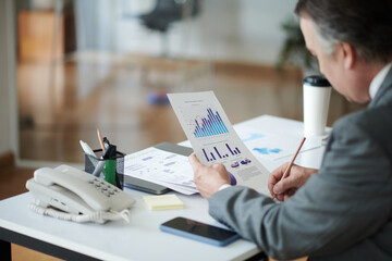 Cropped image of businessman checking charts and graphs at his desk