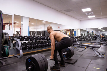 Fototapeta na wymiar Rear view of a strong man doing deadlifts in a gym