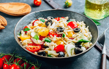 Mediterranean orzo salad with black olive, basil, red onion, tomato and cucumber.
