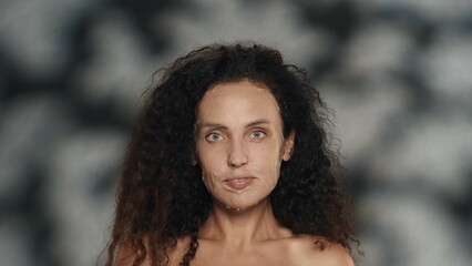 Woman in white cosmetic sheet mask on her face. Portrait of a seminude woman in the studio on a black background with highlights. The concept of beauty, cosmetology, care.