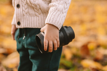 The child holds a thermo mug in his hand. Walk through the autumn forest