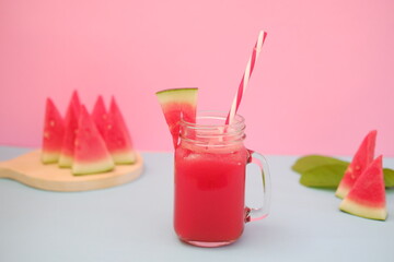Watermelon smoothie in a glass jar with straws as a background