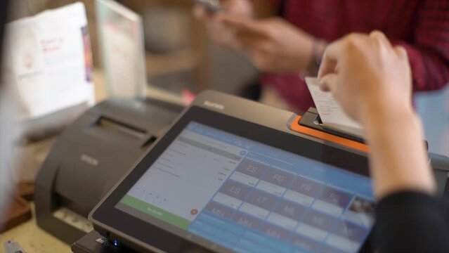 Receipt in hand. The seller shows the receipt to the customer during the buying process. The seller tears up and checks the receipt and gives the buyer from the cash register.
