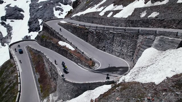 two motorcyclists ride along a scenic mountain road in the alps, as a drone captures spectacular aerial footage. Majestic beauty of the stelvio pass in the Alps in all their glory.