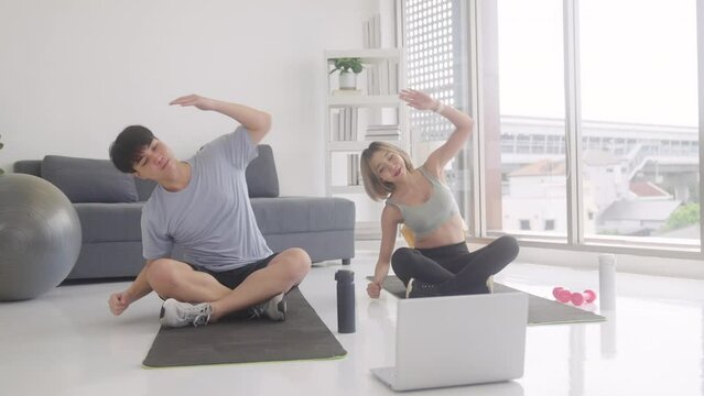 Healthy couple exercising at home, using laptop