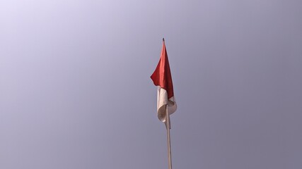 The red and white Indonesian flag flutters against a blue sky background