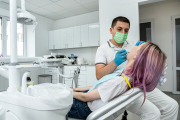 Fototapeta na wymiar male dentist treats a girl with caries using tools.
