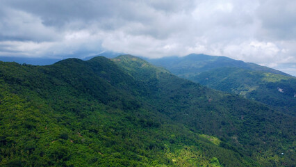 Rain clouds over mountain peaks on a tropical island. The slopes and peaks of the mountains are covered with tropical rainforest.