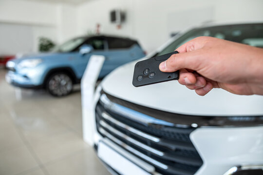 closeup of salesperson holding key against new modern car at showroom