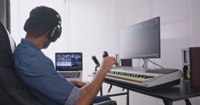 A musician is creating new music in his home studio. A composer is using modern equipment to help create a melody.