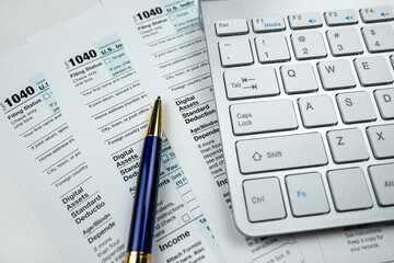pen with computer keyboard on business finance tax form, office desk