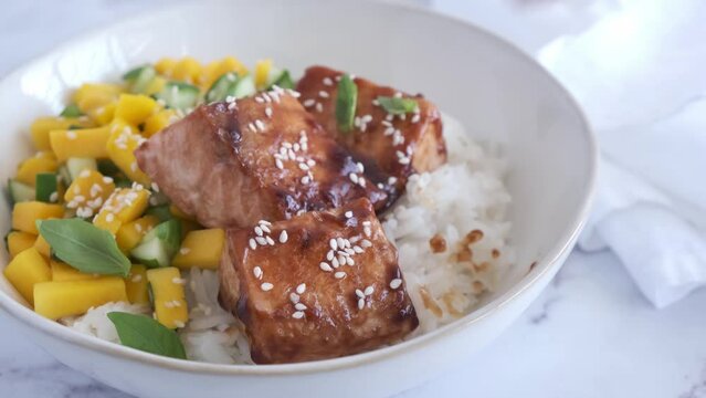 Teriyaki salmon with rice and mango in a white bowl. Asian cuisine concept.
