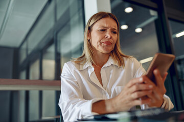 Worried woman manager holding phone before calling to client while sitting in office