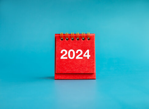 Happy new year 2024 banner background. 2024 white numbers year on red small desk calendar cover standing on light blue background, minimal style. Business goals plan and success schedule concepts.