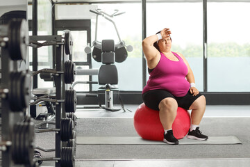 Fototapeta na wymiar Tired overweight woman sitting on a fintess ball