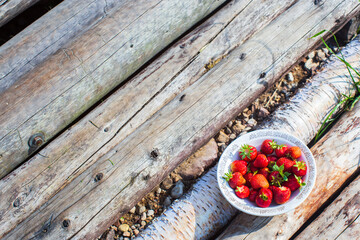 Close-up strawberry crop lying in a plate on rural wooden steps. The concept of healthy food, vitamins, agriculture, market, strawberry sale