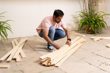 Man distributing the slats for the assembly of the furniture of his house. Lifestyle concept.