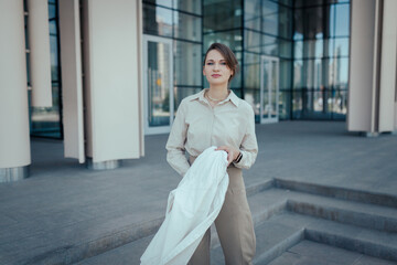 Confident stylish caucasian business woman 25 years old look at camera against the backdrop of an office business center.
