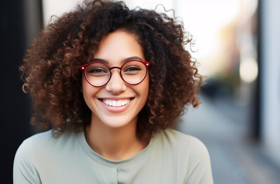 A biracial young woman with African frizzy hair wearing clean lined and red frame glasses with beautiful smiling in outdoor at sunny day - Powered by Adobe