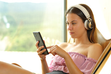 Teen listening music on a chair using phone and headphone