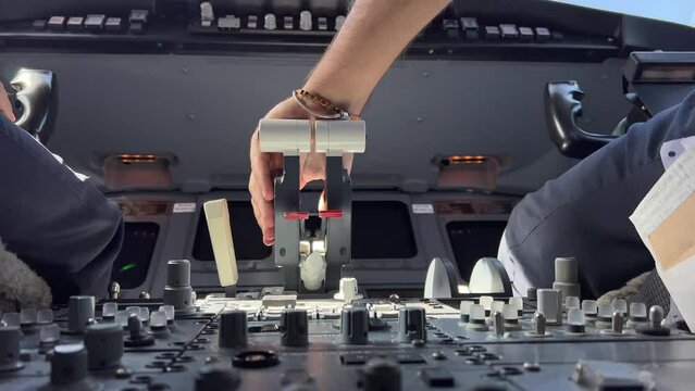 Copilot adjusts his seat before handling the engine thrust levers in a real flight. Low angle view.