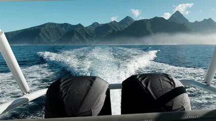 Speed boat with two hug outboard engines while underway with spectacular Tahiti mountains on the horizon