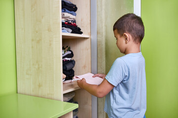 The boy puts washed and ironed clothes in the closet. Homework.