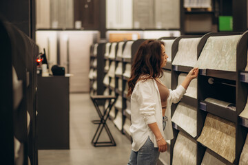 A young woman in a store chooses Wallpaper for her home. Concept of repair and shopping.