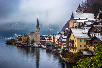 Hallstatt, Austria - Classic view of world famous Hallstatt, the Unesco protected lakeside town with Hallstatt Lutheran Church on a cold foggy day with snowy winter rooftops at Salzkammergut region