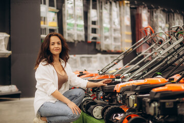 Fototapeta na wymiar a woman buys a lawnmower in a store