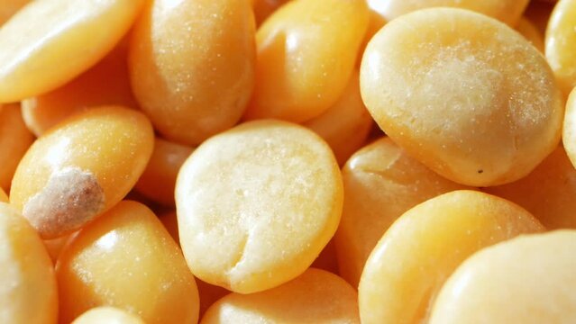 Macro video, split pigeon peas (Toor Dal) come to life. Tiny golden pulses reveal intricate textures as they tumble and shift, showcasing nature's artistry at a microscopic level.
