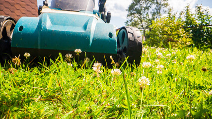 Lawn mover on green grass in modern garden or backyard. Machine for cutting lawns. Gardening care tools and equipment. Process of lawn trimming