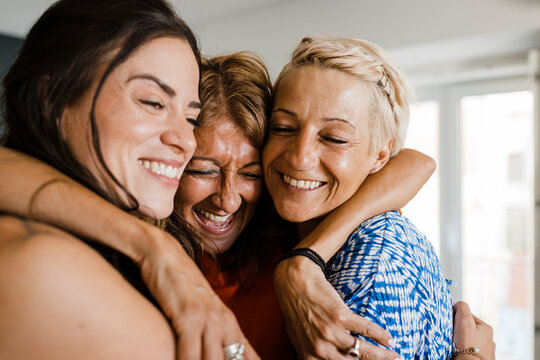 Cheerful friends hugging each other in apartment