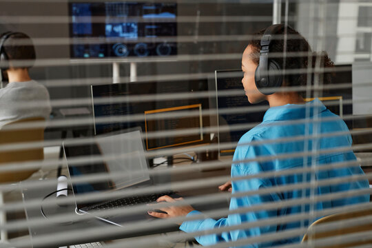 Young computer programmer working on desktop PC and laptop in office