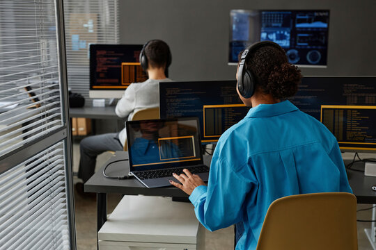 Young computer programmer with colleague working on desktop PC at desk