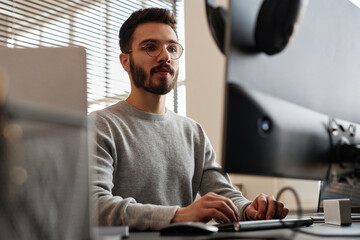 Smiling young IT professional working on computer