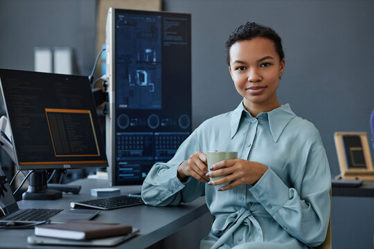 Smiling IT professional sitting with coffee cup at desk