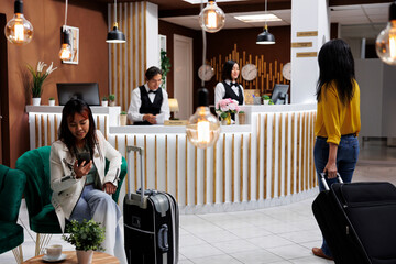 Guests arrive on vacation and are standing at cozy hotel entrance with luggages, preparing to be...