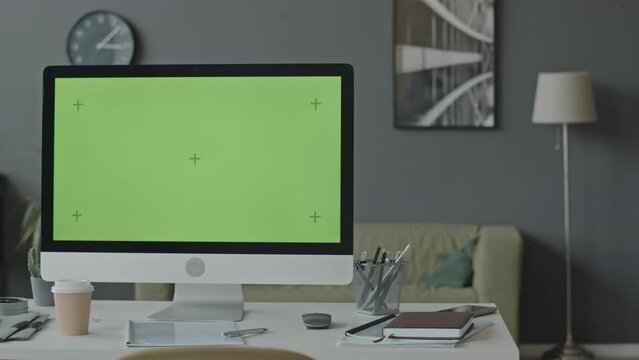 No people shot of computer monitor with green mockup template screen on desktop in office