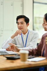 Asian man employee listening attentively listening attentively during corporate meeting.