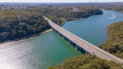 Aerial drone view rising up over Alfords Point Bridge across Georges River in Southern Sydney, New South Wales, Australia looking toward Padstow Heights      