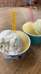 ice cream for two, two bowls of ice cream, scoops of ice cream in paper cups with spoons, wooden background