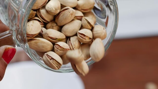 A jar with pistachios, a glass below with water, and more pistachios in it
