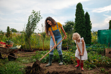 Mother and daughter digging a hole to plant seeds
