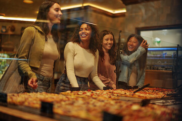 Young hungry girlfriends at the pizzeria talking to a baker
