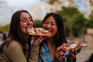 Friends sharing a slice of pizza on the streets